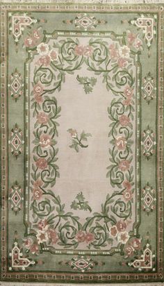 an old rug with flowers and vines on the border is shown in light green, pink, and white colors