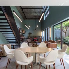 a dining room table with white chairs next to a staircase leading up to the second floor