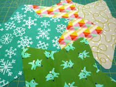 several pieces of fabric are laid out on a cutting board, with snowflakes in the background