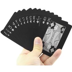 a hand holding four playing cards in front of the camera, which are black and white