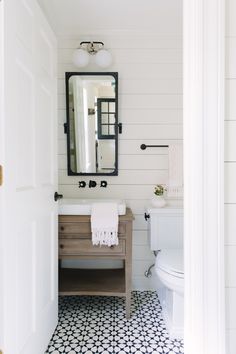 a bathroom with black and white tile flooring, a mirror over the sink and a toilet