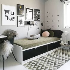 a bedroom with white walls, black and white decor and pictures on the wall above the bed