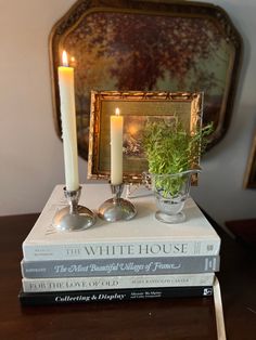 a couple of books sitting on top of a wooden table next to a candle holder