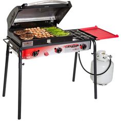 a red and black grill with food on it's side next to a propane tank