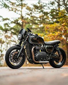 a black motorcycle parked on the side of a road next to some trees and bushes