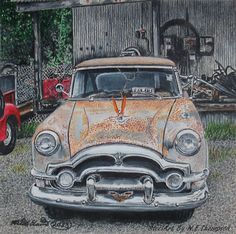 an old rusted car parked in front of a barn