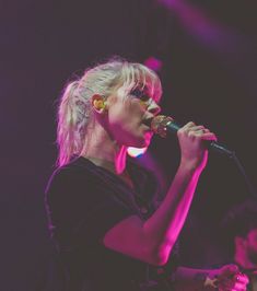 a woman singing into a microphone on stage