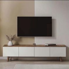 a flat screen tv mounted to the side of a white cabinet in a living room