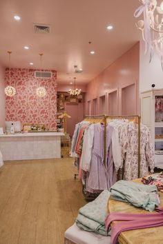 the inside of a clothing store with clothes on racks