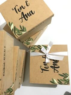 four boxes with green leaves on them are wrapped in brown paper and tied with white ribbon