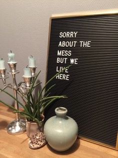 there is a vase and candles on the table next to a sign that says sorry about the mess but we live here