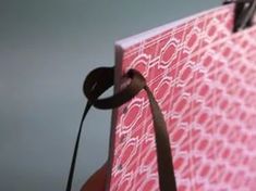 a close up of a pink and white box with a brown ribbon tied to it