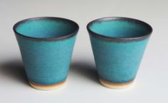 two blue cups sitting next to each other on a table