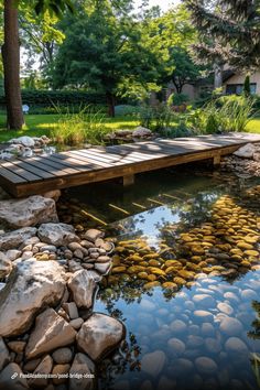 a wooden bridge over a small pond surrounded by rocks