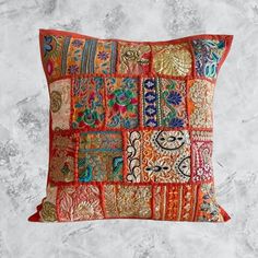 an orange pillow with colorful patchwork on the front and back, sitting on a marble surface