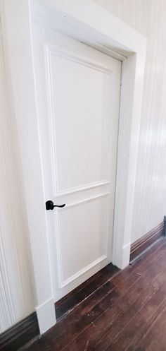 an open door in a white room with wood flooring