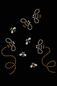 some beads are arranged in the shape of dragonflies on a black background with orange and white pearls