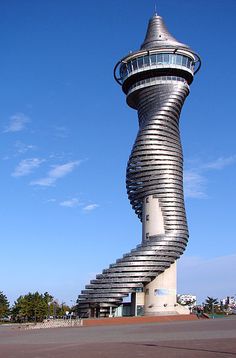 a very tall building with a spiral staircase going up it's side in front of a blue sky