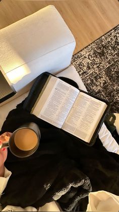 an open book and cup of coffee on a bed