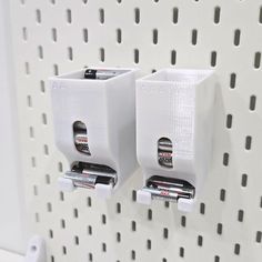 two white toothbrush holders on a wall with holes in the middle and batteries attached to them