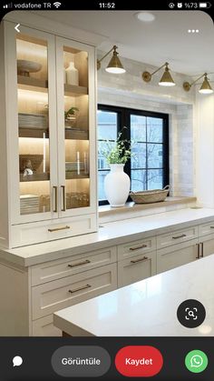 a large kitchen with white cabinets and marble counter tops in front of a black window