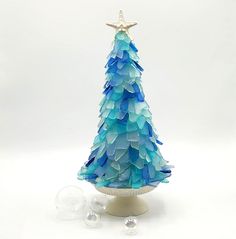 a blue glass christmas tree sitting on top of a table