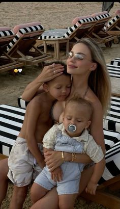 two women and a baby are sitting on beach chairs with their faces covered by sun glasses