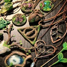 many different necklaces are laying on a table together, some have leaves and other things attached to them