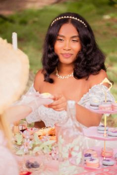 a woman sitting at a table with cupcakes on it and other items around her