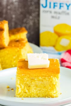 a piece of cornbread cake on a plate next to a carton of jelly