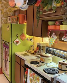 a green refrigerator freezer sitting inside of a kitchen next to a stove top oven