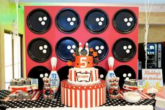 a birthday cake and party supplies on a table in front of a wall with plates