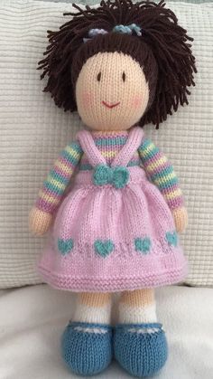 a knitted doll sitting on top of a bed