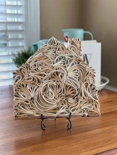 an intricate wooden sculpture sitting on top of a table next to a cup and saucer