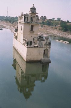 an old tower sitting in the middle of a body of water