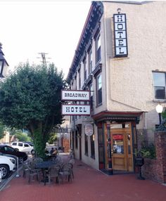 a hotel sign on the side of a building with tables and chairs in front of it