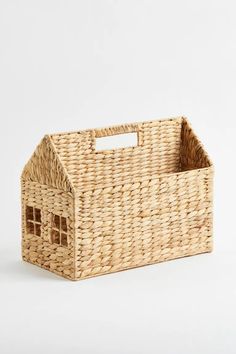 a wicker basket with a small house on the front and side, sitting against a white background