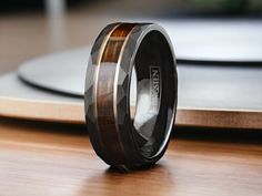 a wedding ring with wood inlays on top of a wooden table