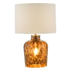 a brown glass lamp with a white shade on the base and a light bulb attached to it