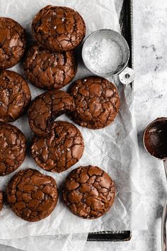 chocolate cookies on parchment paper with spoons and salt in the bowl next to them