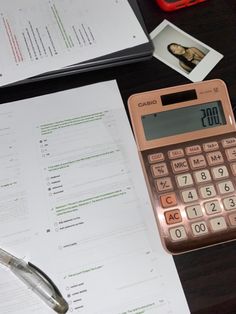 a calculator sitting on top of a table next to papers and a pen