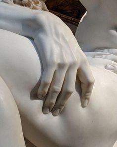 a close up of a white statue with hands on it