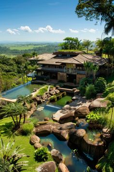 an aerial view of a house with a pool in the foreground and lush vegetation surrounding it