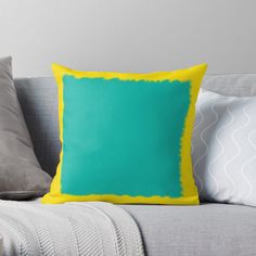 a blue and yellow pillow sitting on top of a gray couch next to two white pillows