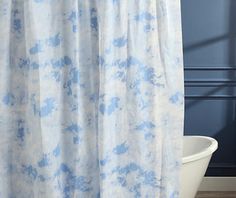 a white tub sitting next to a shower curtain in a bathroom with blue walls and wooden floors