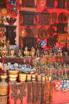 an assortment of decorative items on display in a store window with red walls and wooden carvings