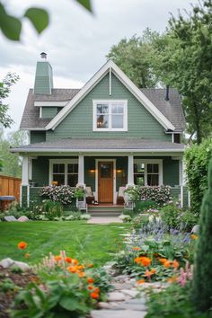 a green house with flowers in the front yard