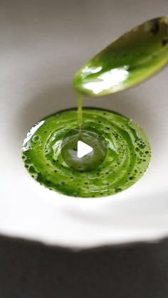 a green liquid is being poured into a white bowl with an odd shaped object in the middle