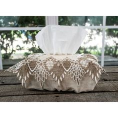 a tissue box with lace on it sitting on a wooden table