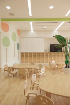 an empty classroom with tables, chairs and a potted plant in the middle of the room